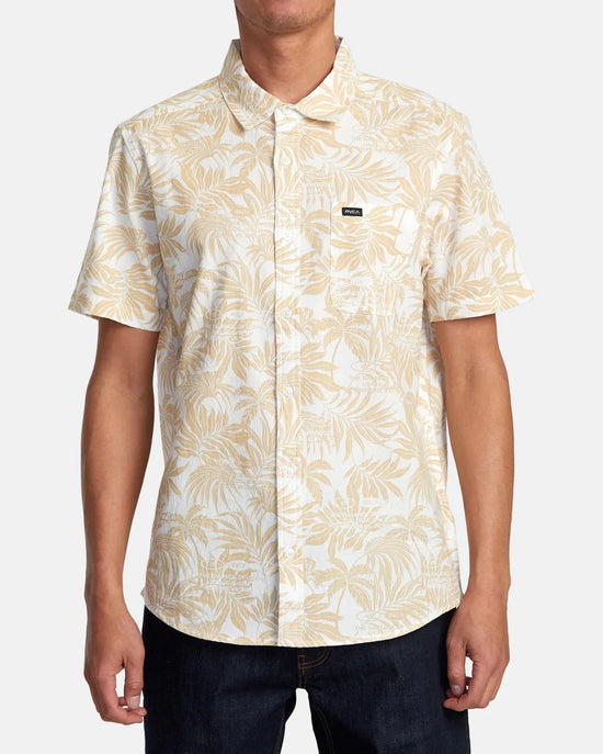 Front view of man wearing a short sleeve button up shirt with a light khaki botanical print throughout