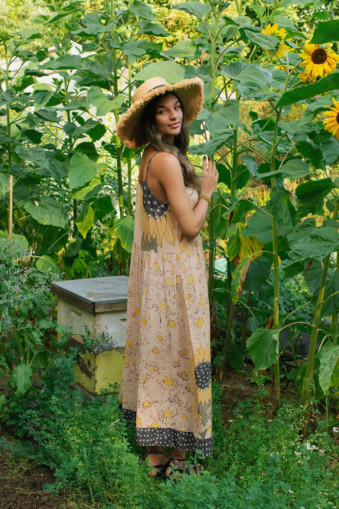 
                      
                        A woman standing near flowers while wearing the Milk & Honey Bohéme Slip Dress by Market of Stars
                      
                    