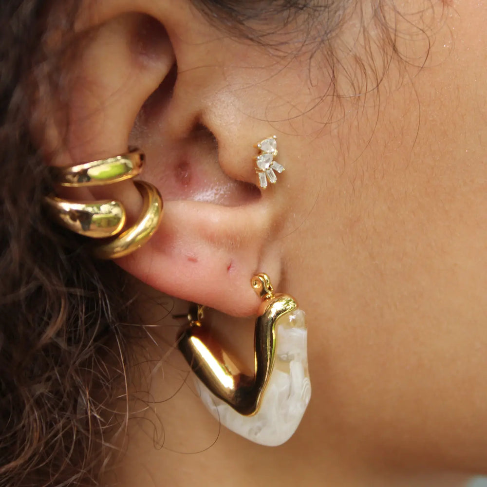 A woman wearing sculptural hoop design earrings