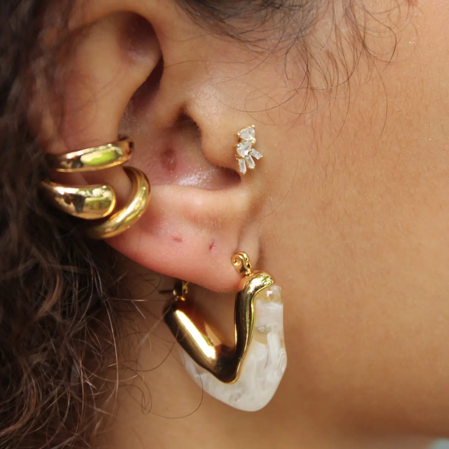 A woman wearing sculptural hoop design earrings