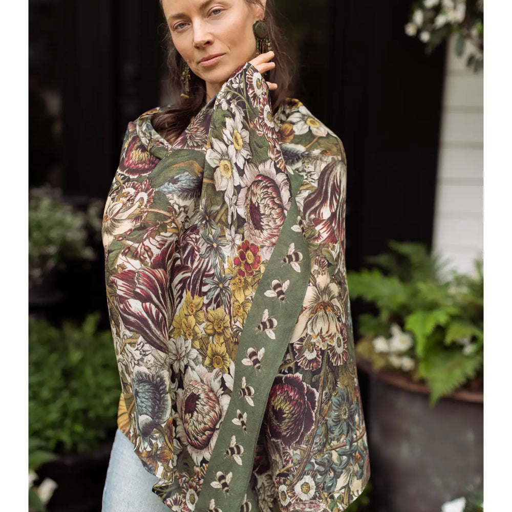 A woman wrapped in the Love Grows Wild Floral Bamboo Scarf with Bees by Market of Stars