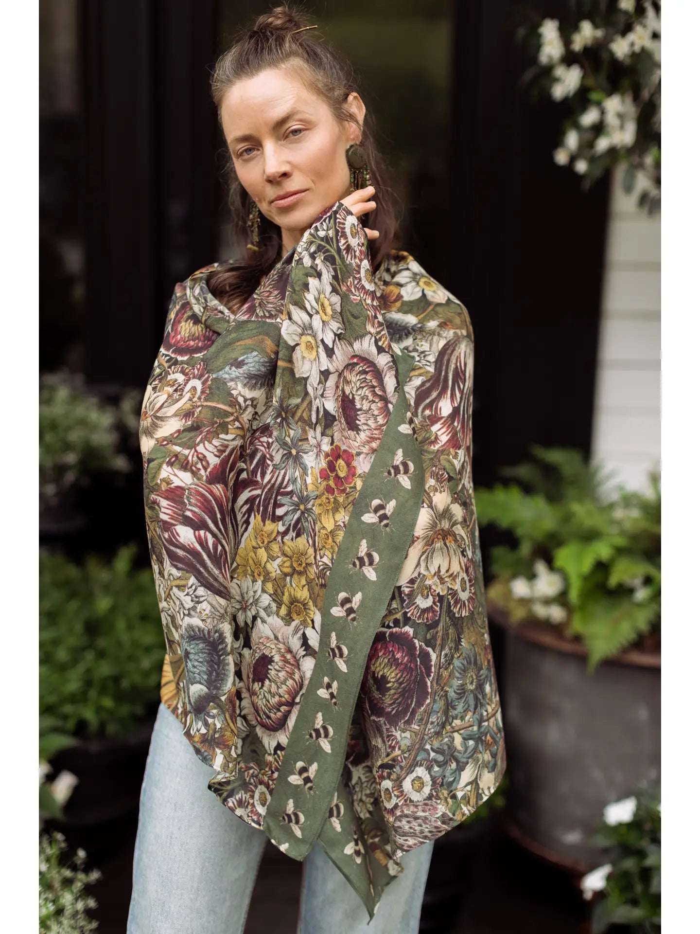 A woman wrapped in the Love Grows Wild Floral Bamboo Scarf with Bees by Market of Stars