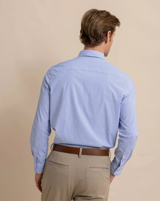 back view of man wearing a blue and white pinstriped long sleeve button up shirt by Southern Tide