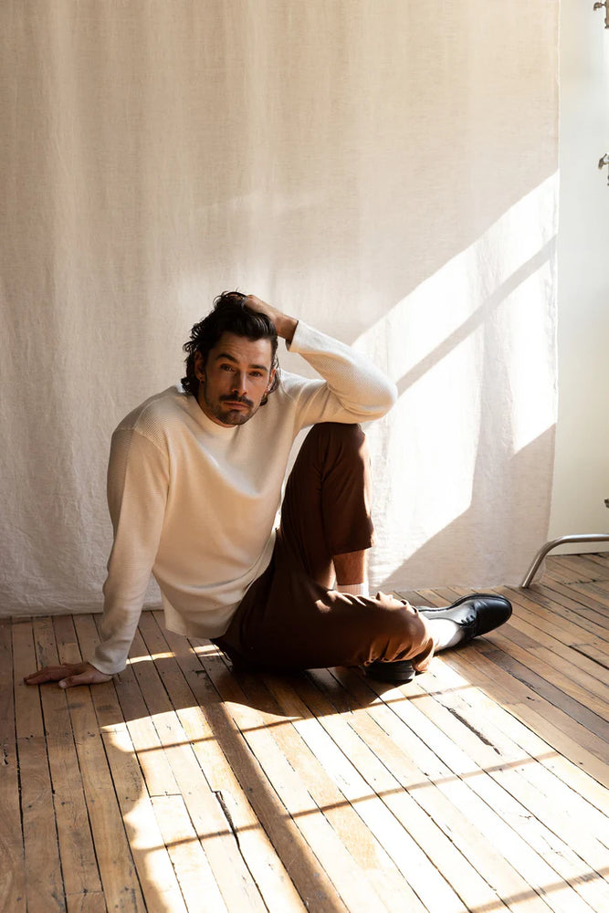 
                      
                        A man posing on the ground while wearing the Vintage White Classic Waffle Knit by Rhythm
                      
                    