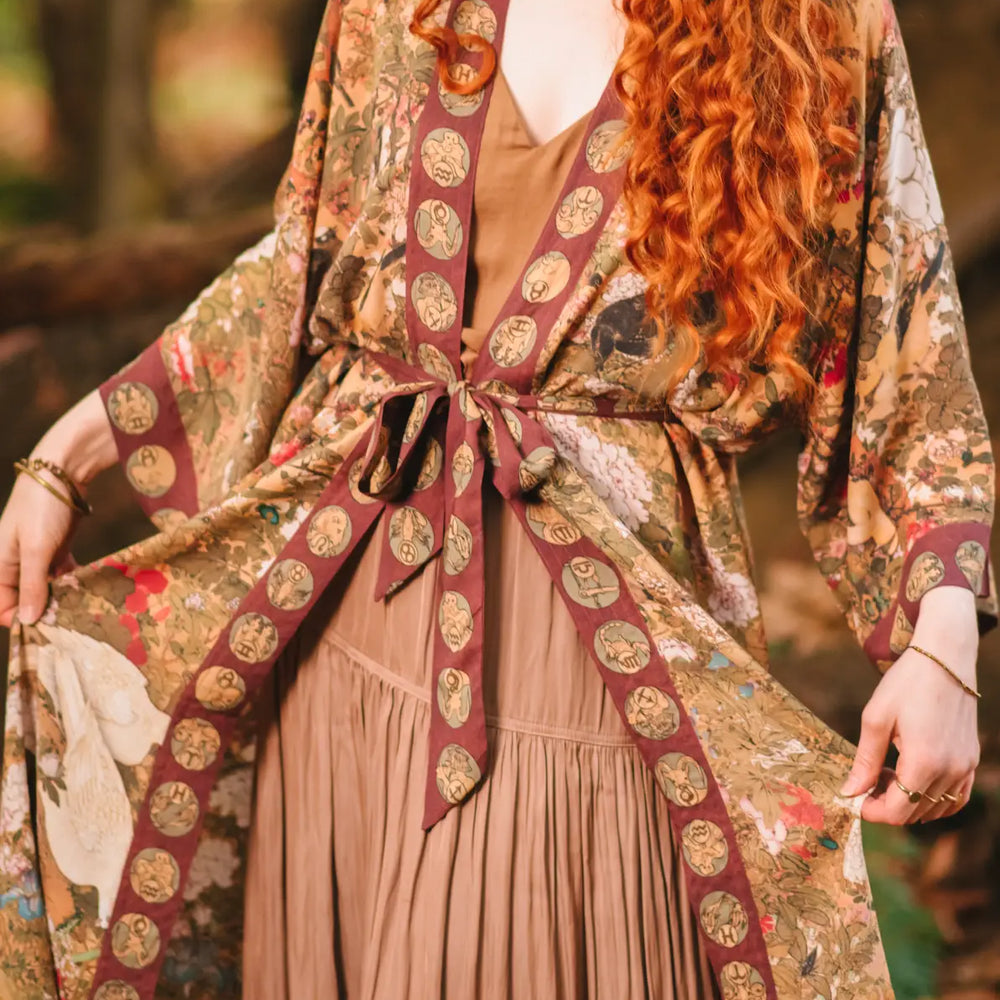 
                      
                        A woman wearing the Dreamweaver Zodiac Kimono Duster Robe by the brand Market Of Stars tied at the waist
                      
                    