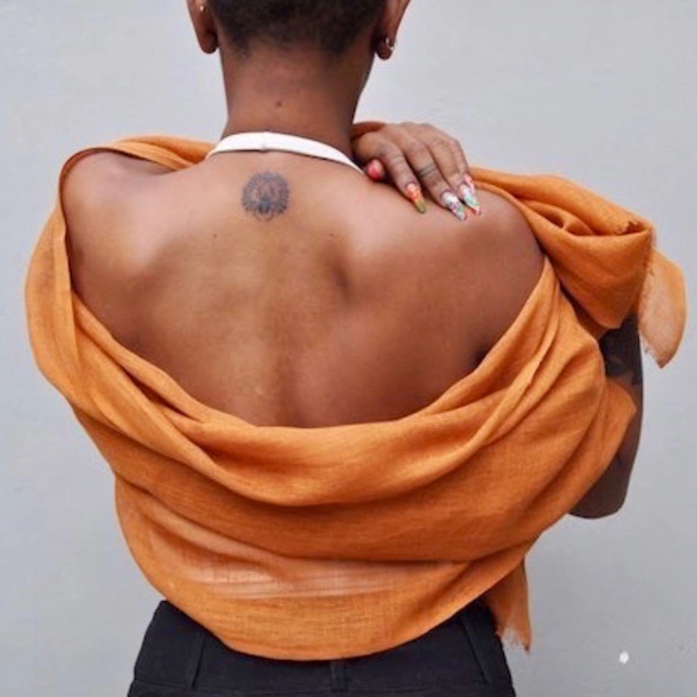 
                      
                        A woman wrapped in the Ethiopian Bronze Gauze Linen Scarf by Slate + Salt
                      
                    