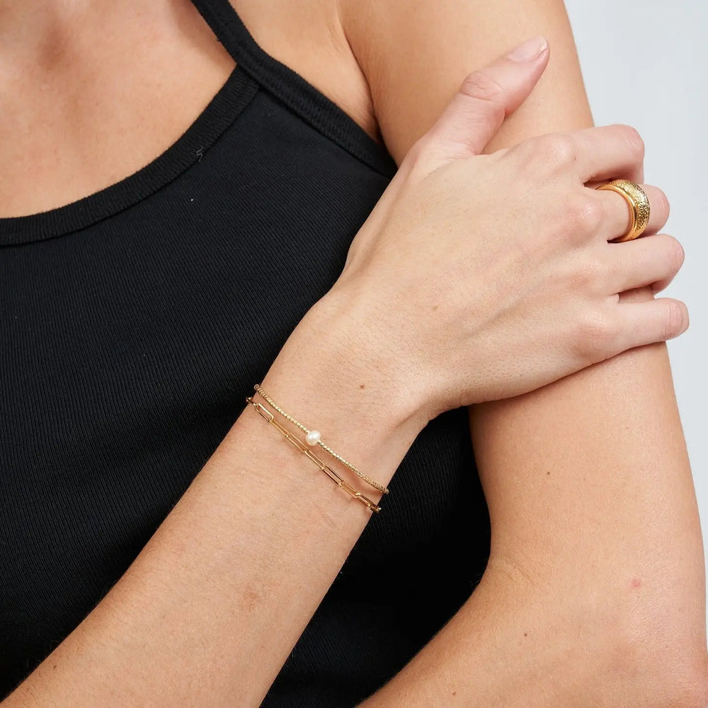 
                      
                        Person wearing the River Gold and Pearl Bracelet by Arms of Eve with another bracelet
                      
                    