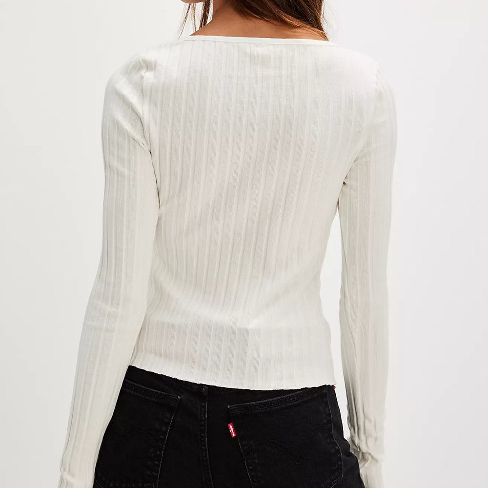 
                      
                        Woman wearing a white ribbed long-sleeve top and black pants on a plain background
                      
                    
