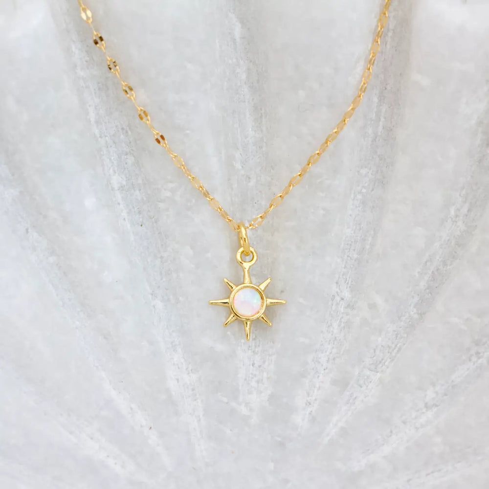 A gold chain necklace with an opal sun pendant