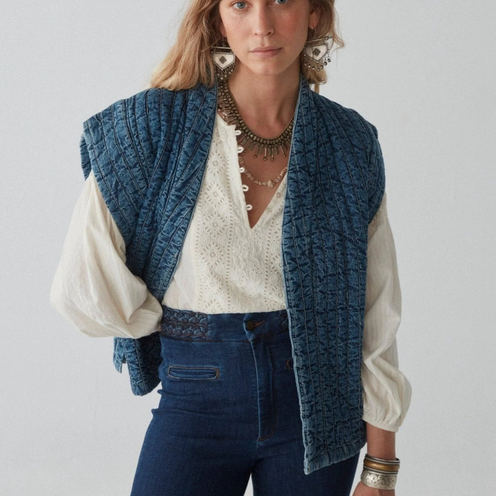 A woman wearing the distressed-washed quilted denim Elsa Jacket by Maison Hotel. 