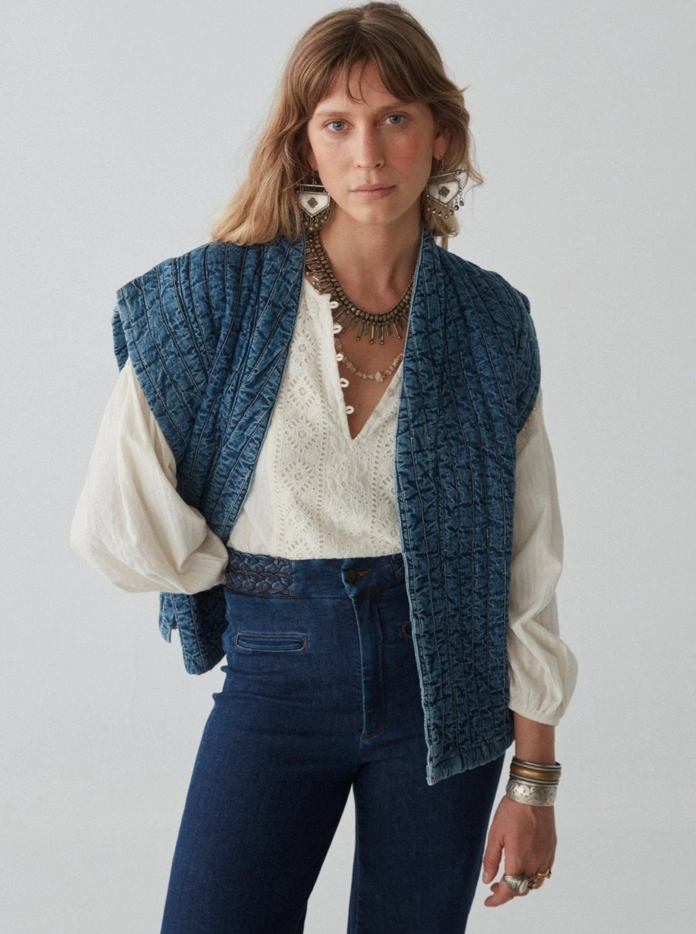 A woman wearing the distressed-washed quilted denim Elsa Jacket by Maison Hotel. 