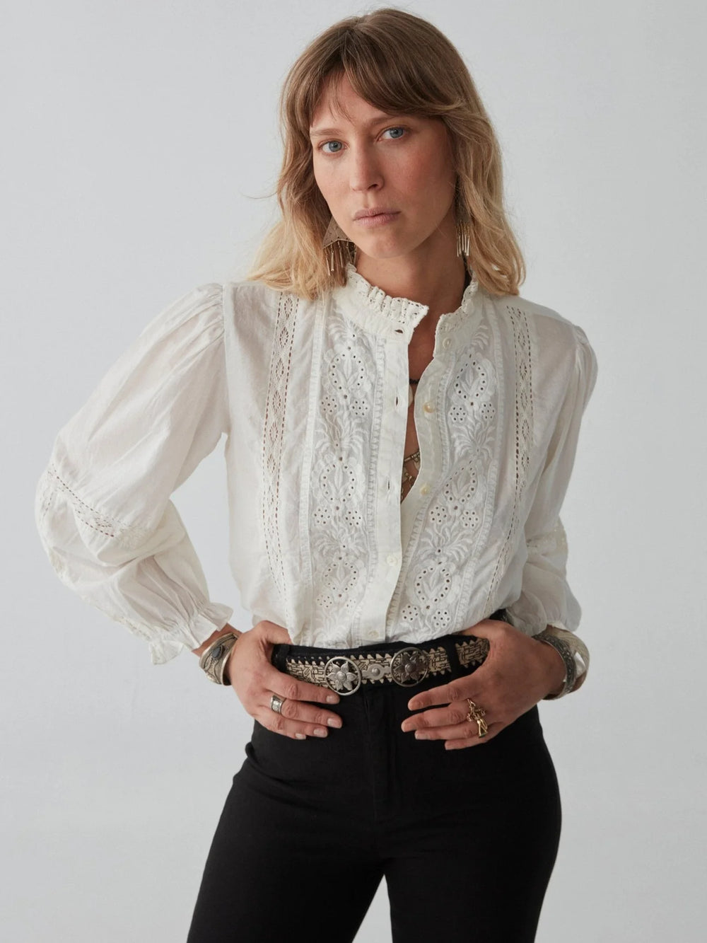 A woman wearing the Emmanuelle Blouse by Maison Hotel tucked into black jeans