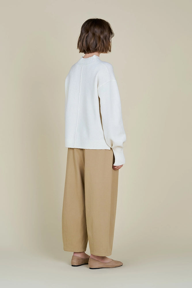 This women's ivory turtleneck sweater features contemporary details like exposed seaming throughout