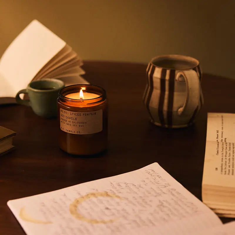 P.F. Candle Co. Spiced Pumpkin Soy Candle  on a desk with other mugs and various papers
