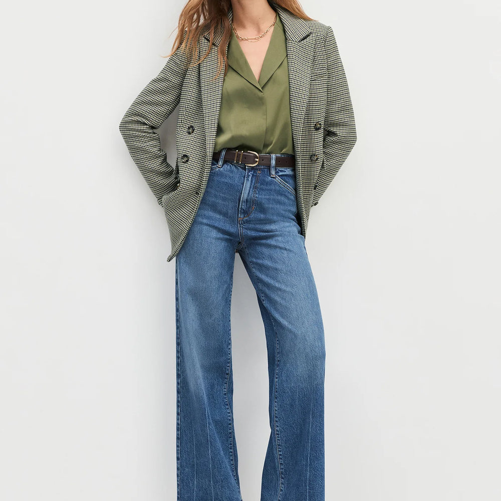 
                      
                        Woman wearing a green blazer, green shirt, and blue jeans on a white background
                      
                    