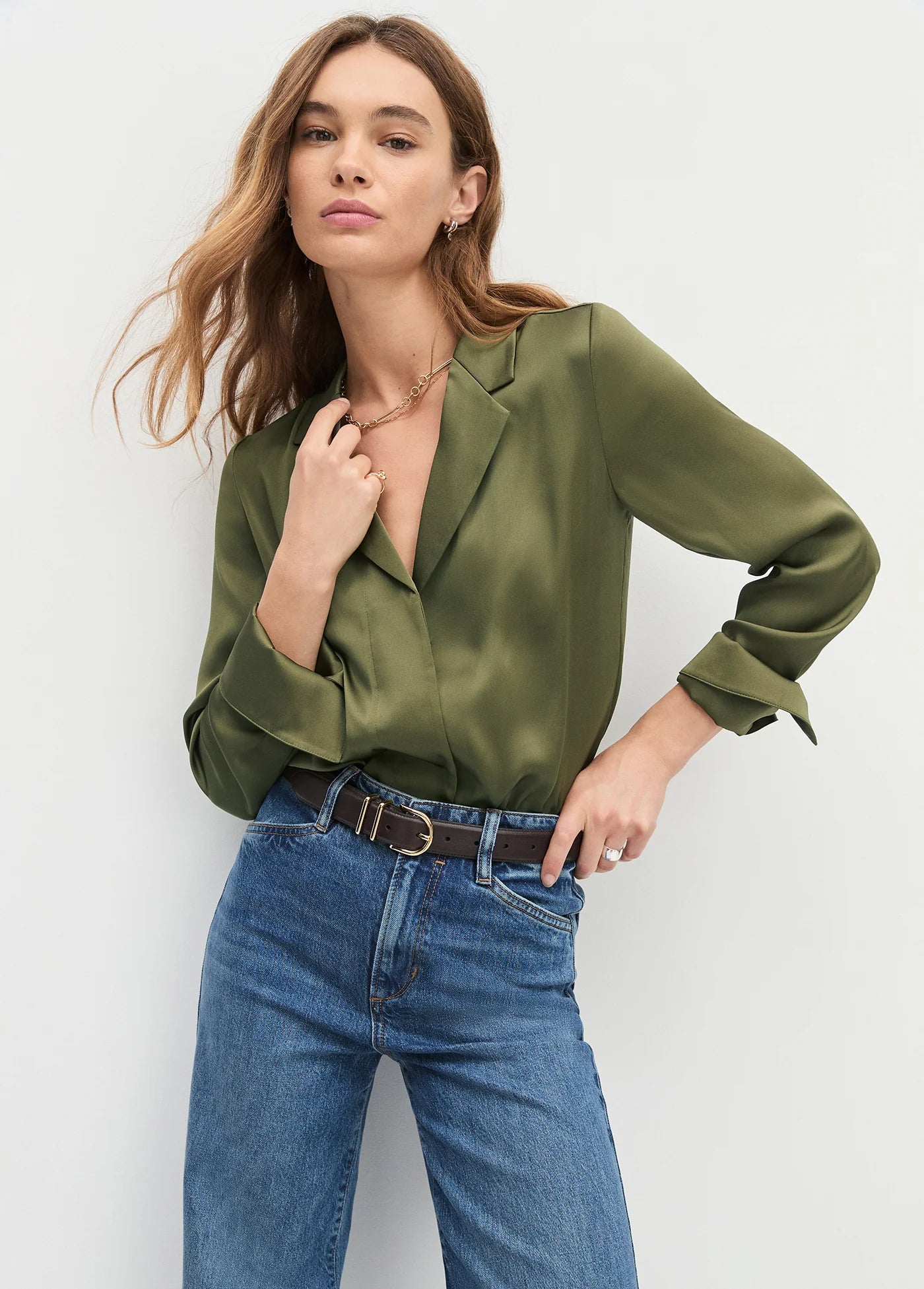 Woman wearing an olive green blouse and blue jeans 