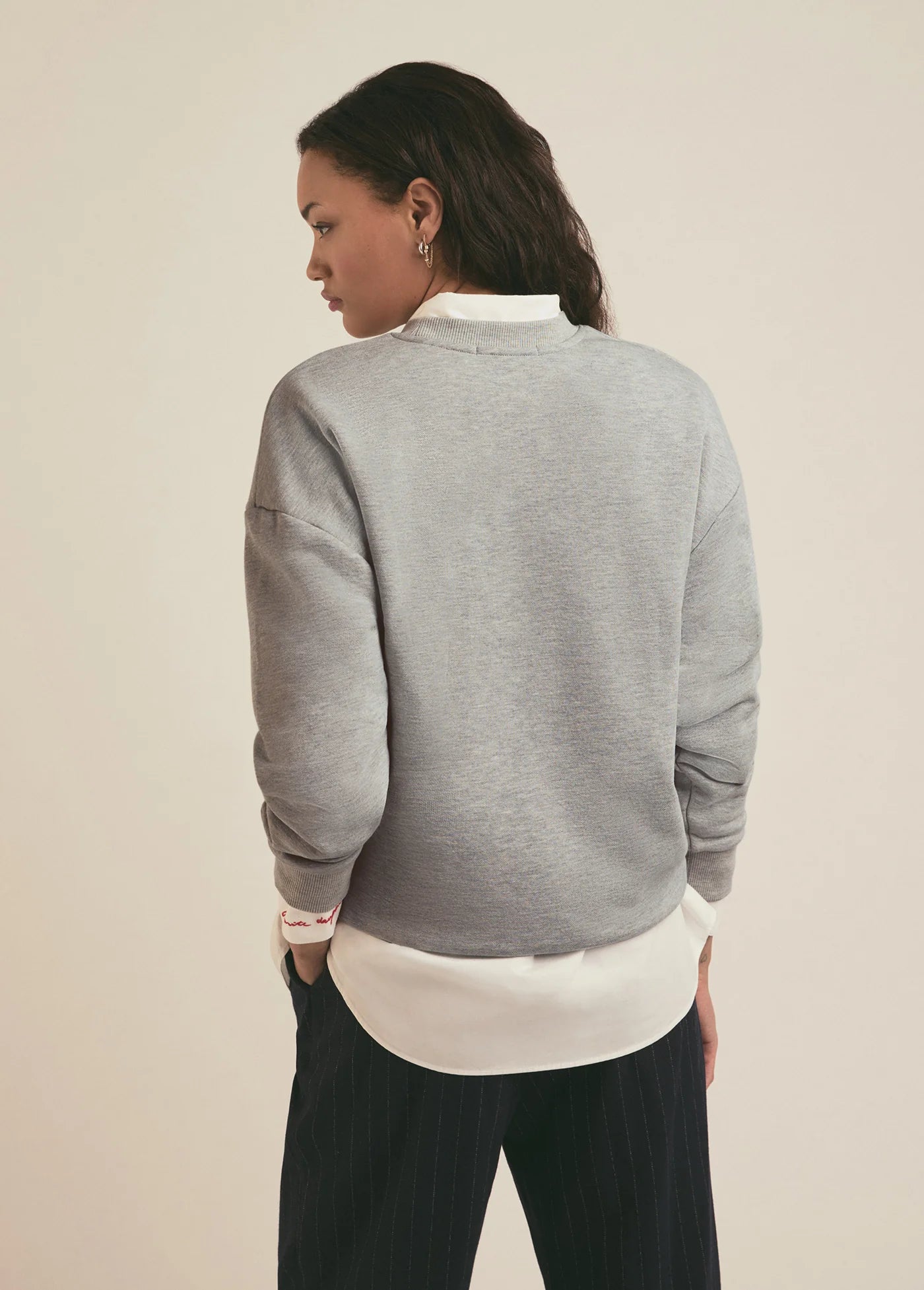 A woman wearing a grey crewneck sweatshirt from Favorite Daughter layered over a white collared shirt