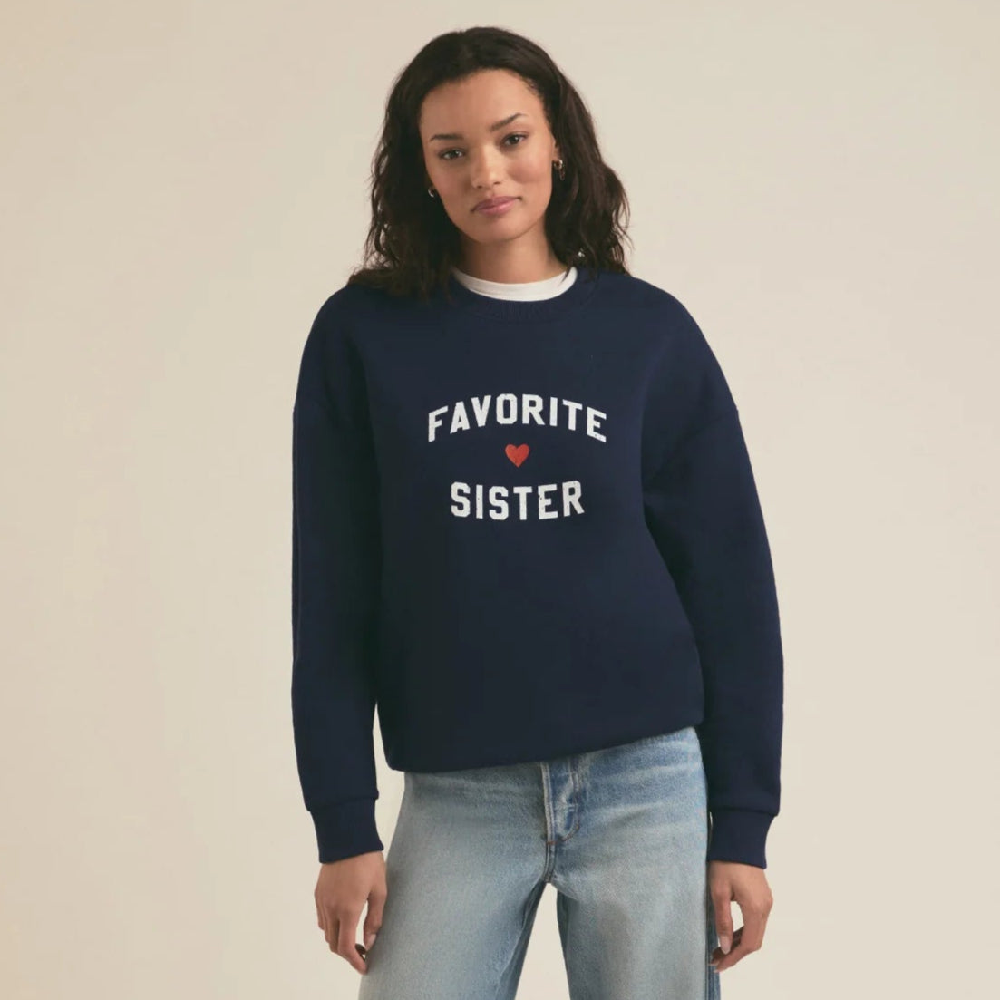 A woman wearing a crewneck sweatshirt that says Favorite Sister