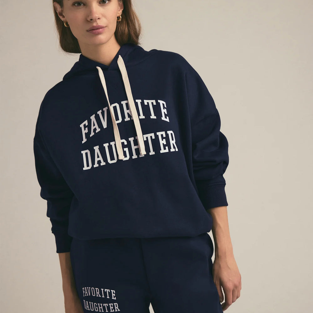 Woman wearing a navy hoodie with 'FAVORITE DAUGHTER' text on a plain background