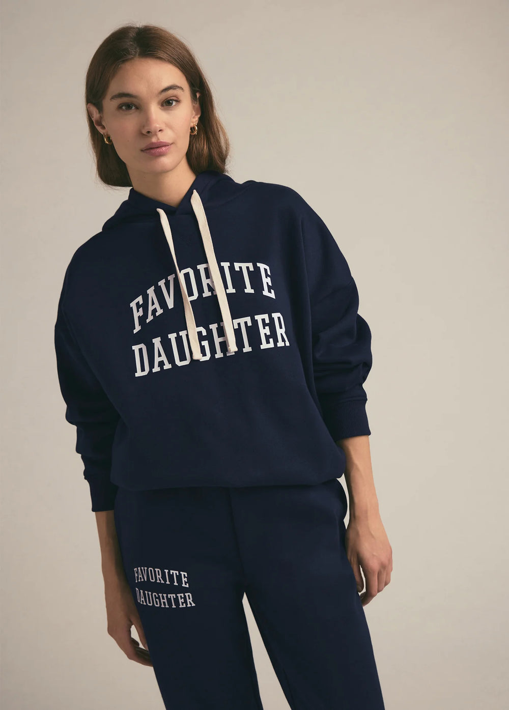 Woman wearing a navy hoodie with 'FAVORITE DAUGHTER' text on a plain background