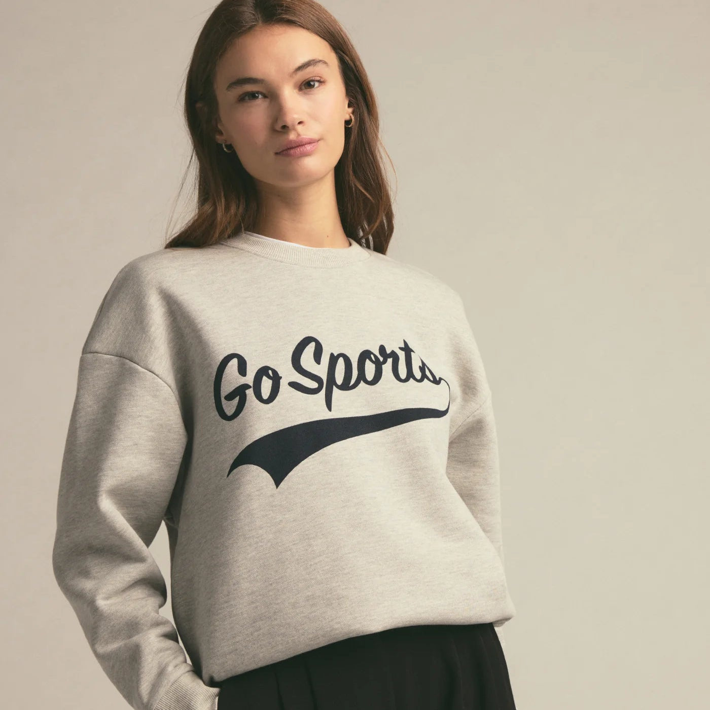 Woman wearing a grey sweatshirt with 'Go Sports' text on the front