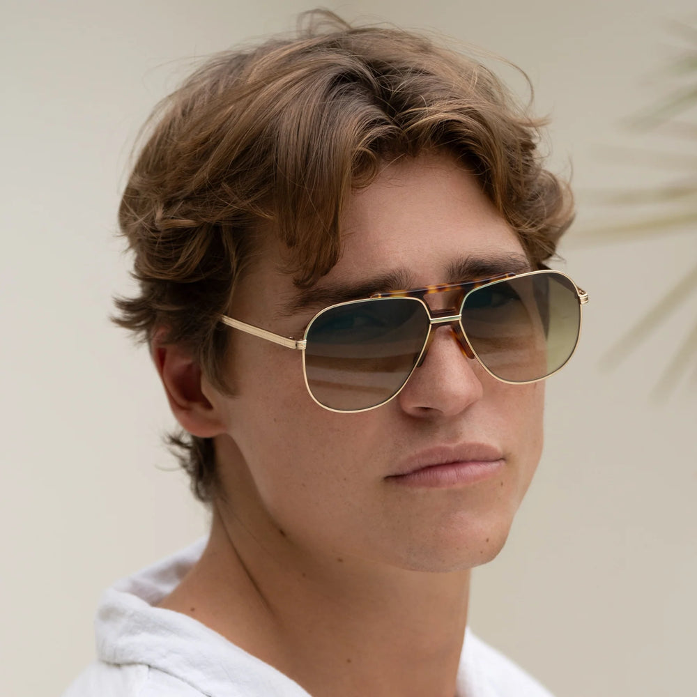 A man wearing the FREYRS Logan Unisex Aviator Sunglasses in the style Gold/Green