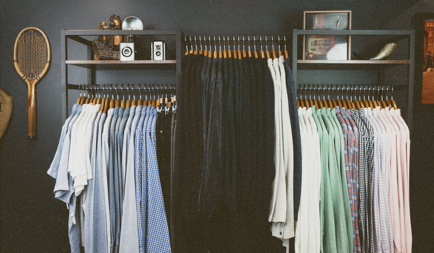 Clothing rack with men's shirts and pants against a dark wall