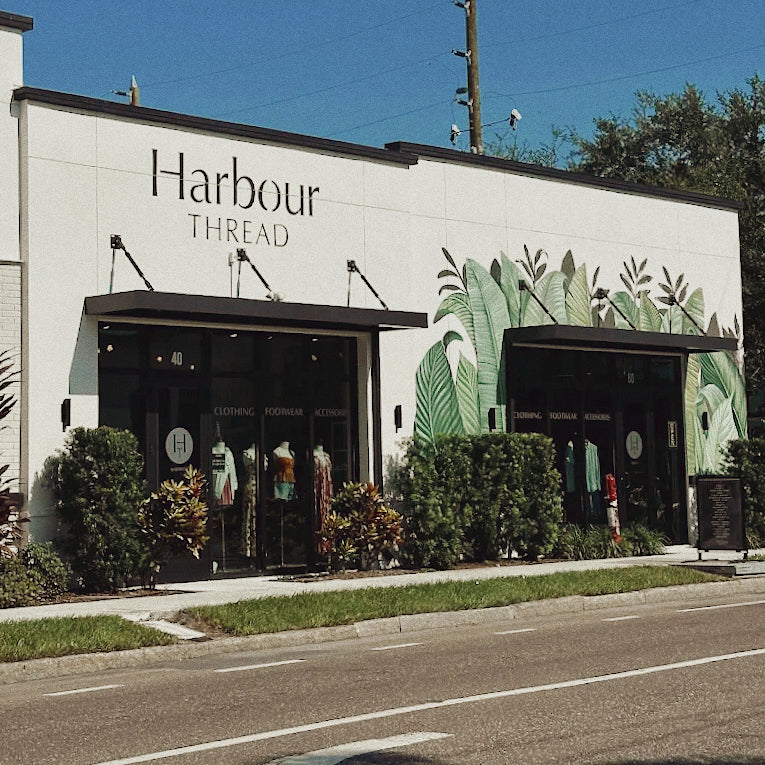 Harbour Thread store exterior with green leafy design on a white wall.