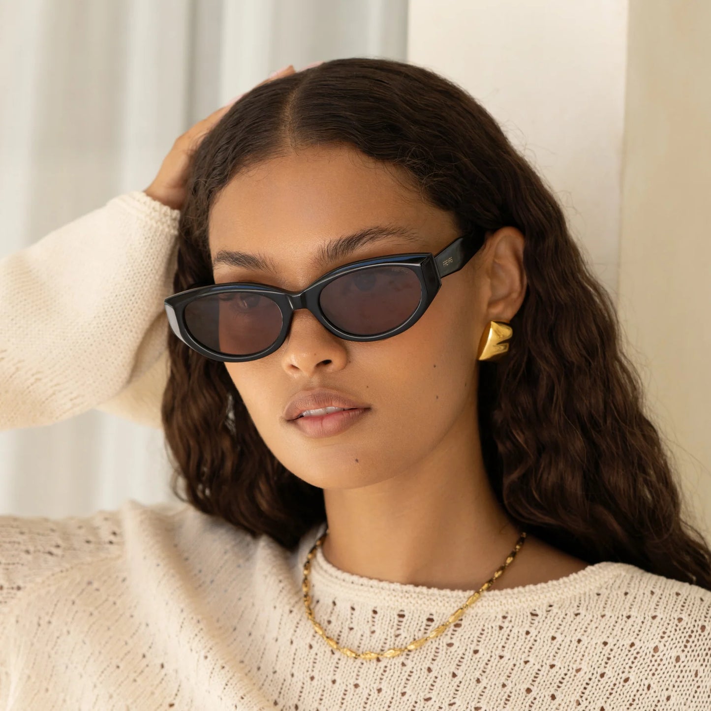 A woman wearing the black FREYRS Ameli Women's Oval Cat Eye Sunglasses