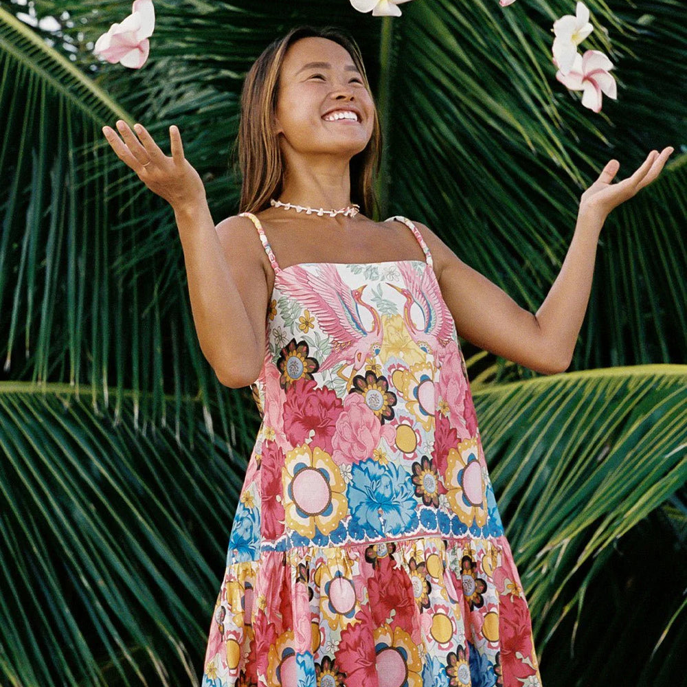 
                      
                        A woman outside wearing the Dancing Birds Scarlett Shift Mini Border Dress by Shore while throwing flower petals in the air
                      
                    