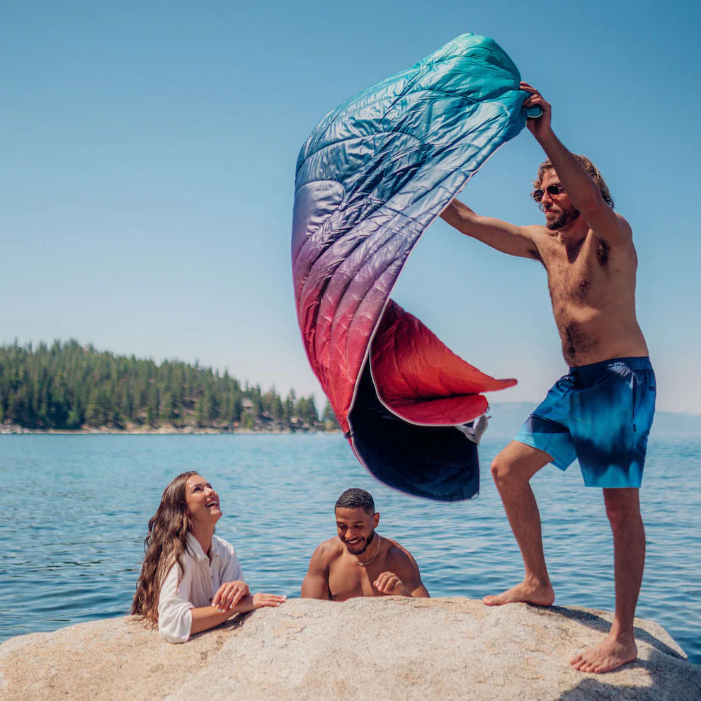 People at the lake using Rumpl's Original Puffy Blanket (1 Person) in the color Arizona Fade