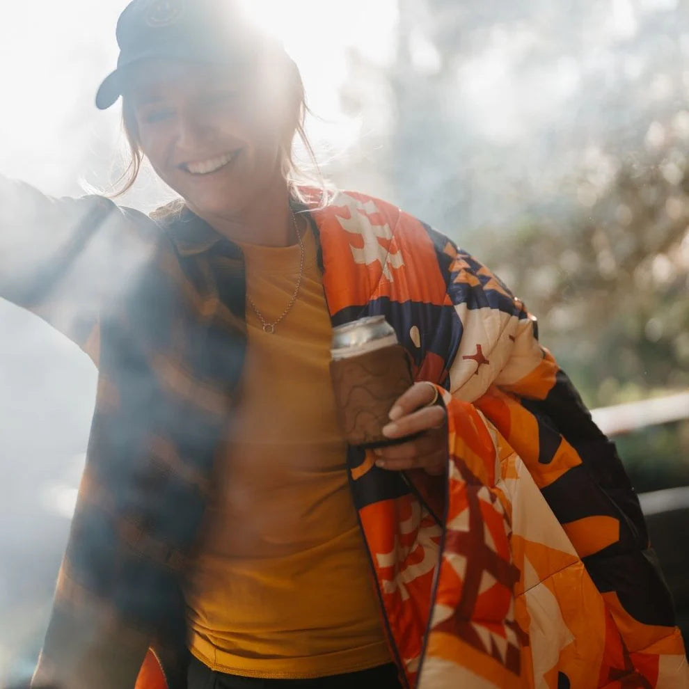 Woman wearing the Sunrise Cabin Original Puffy Blanket by Rumpl