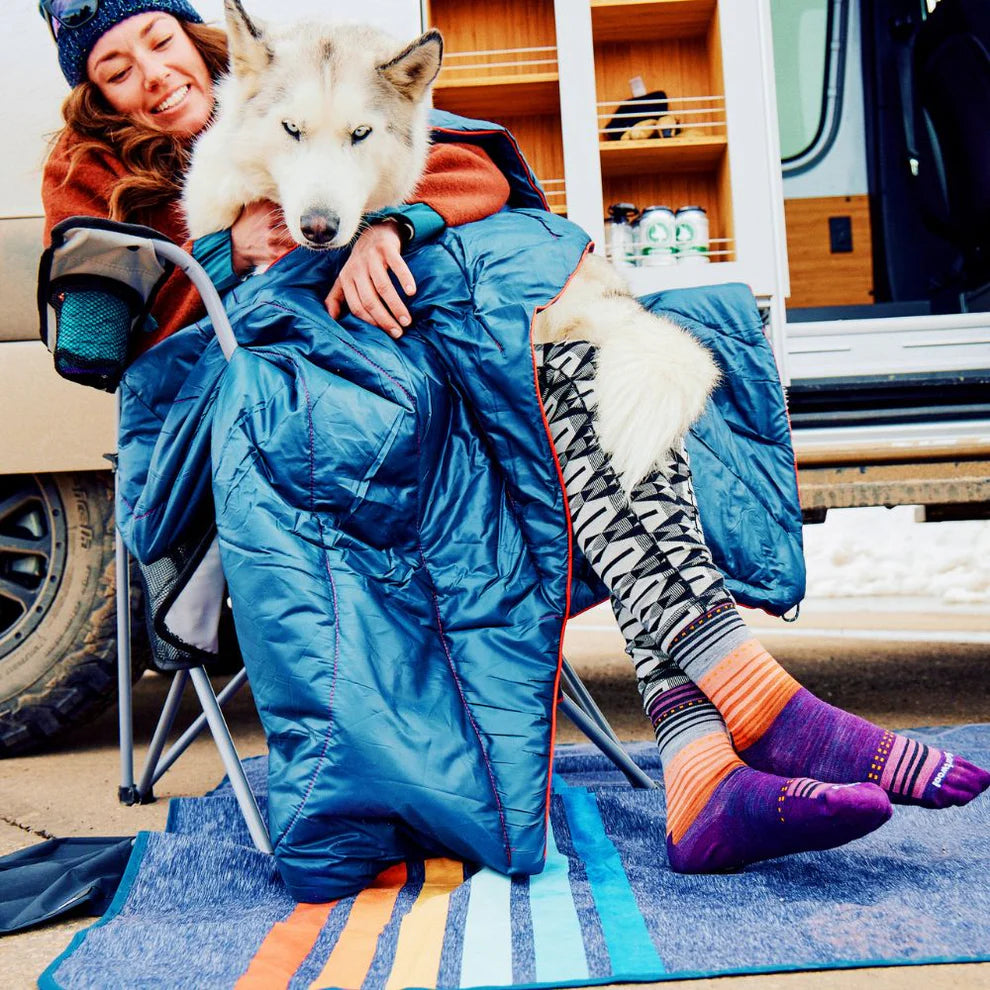 
                      
                        Woman holding her dog wearing Rumpl's Original Puffy Blanket (1 Person) in the color Deepwater
                      
                    