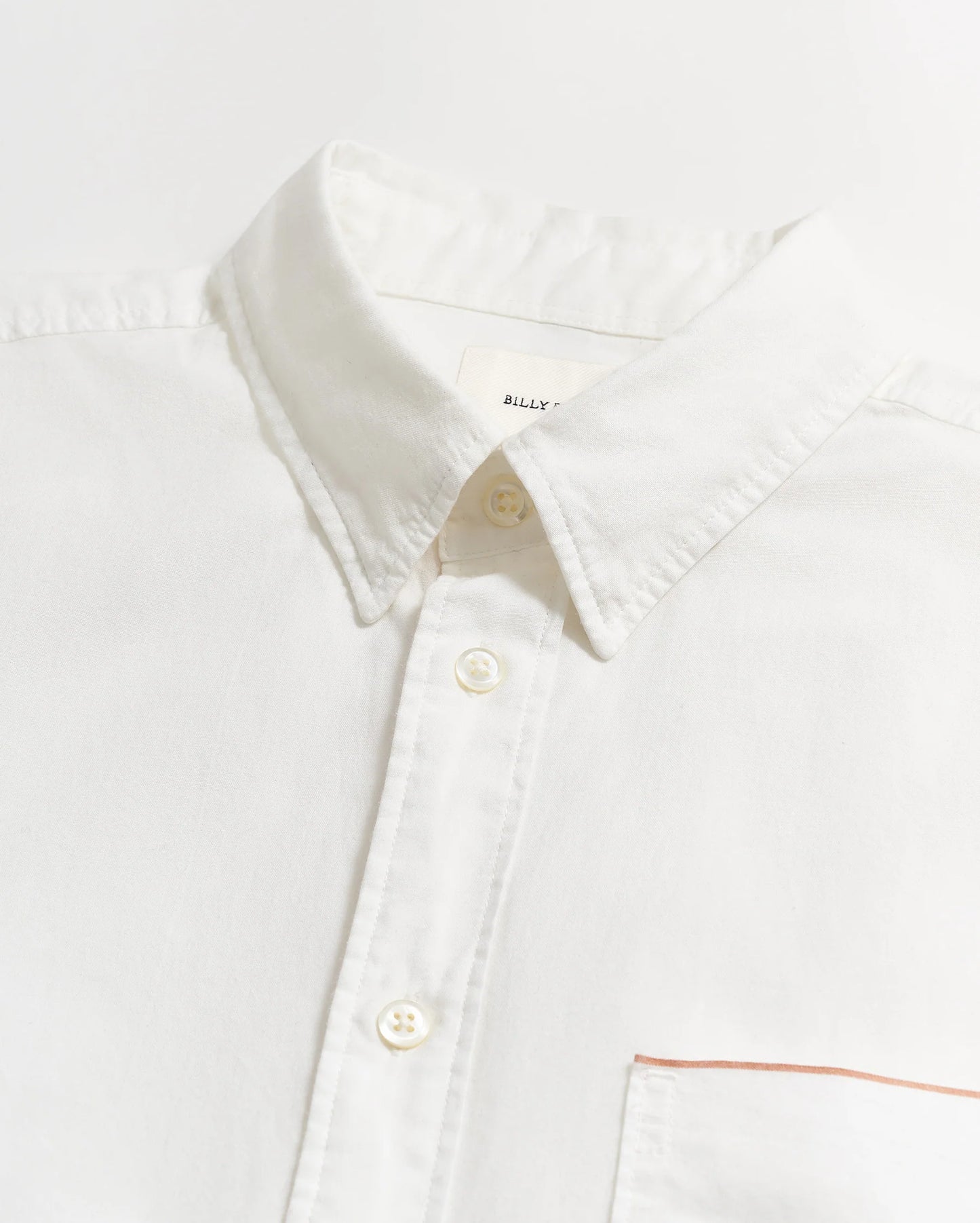 Close up flat lay view of the collar and buttons on a men's white button down shirt by Billy Reid