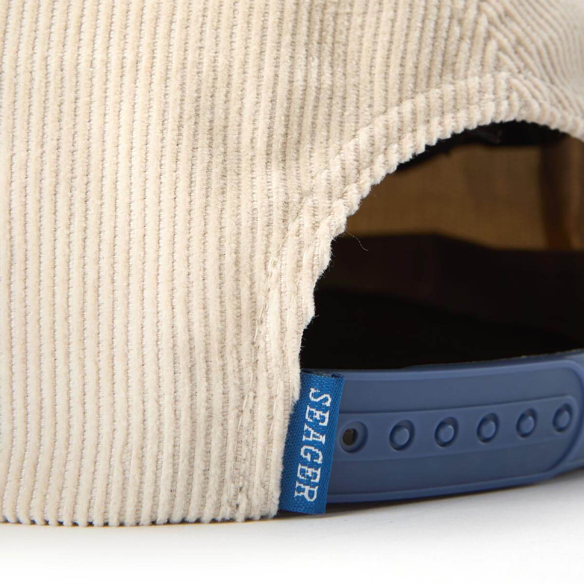 Close-up of a beige textured product with a blue Seager tag.