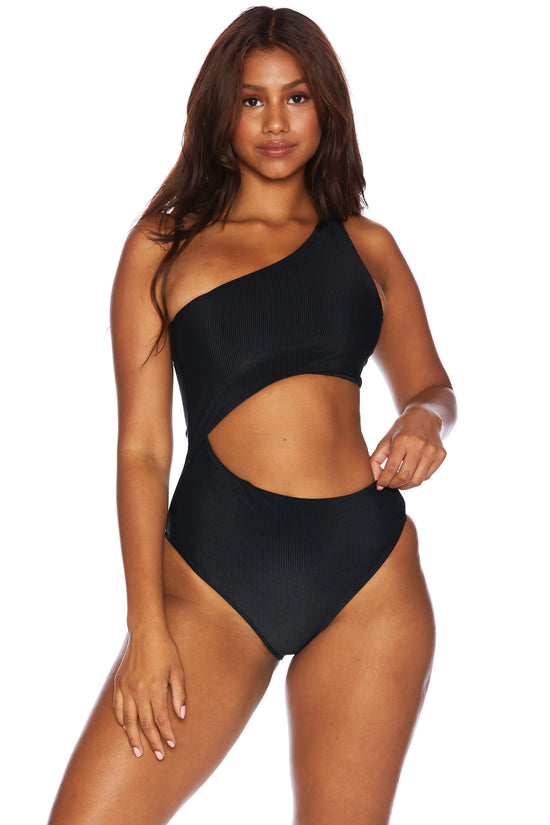 Front view of woman wearing a black, asymmetrical one shoulder one piece swimsuit with a side cutout detail.