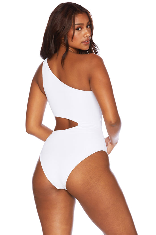 back view of woman wearing a white, asymmetrical one shoulder one piece swimsuit with a side cutout detail.