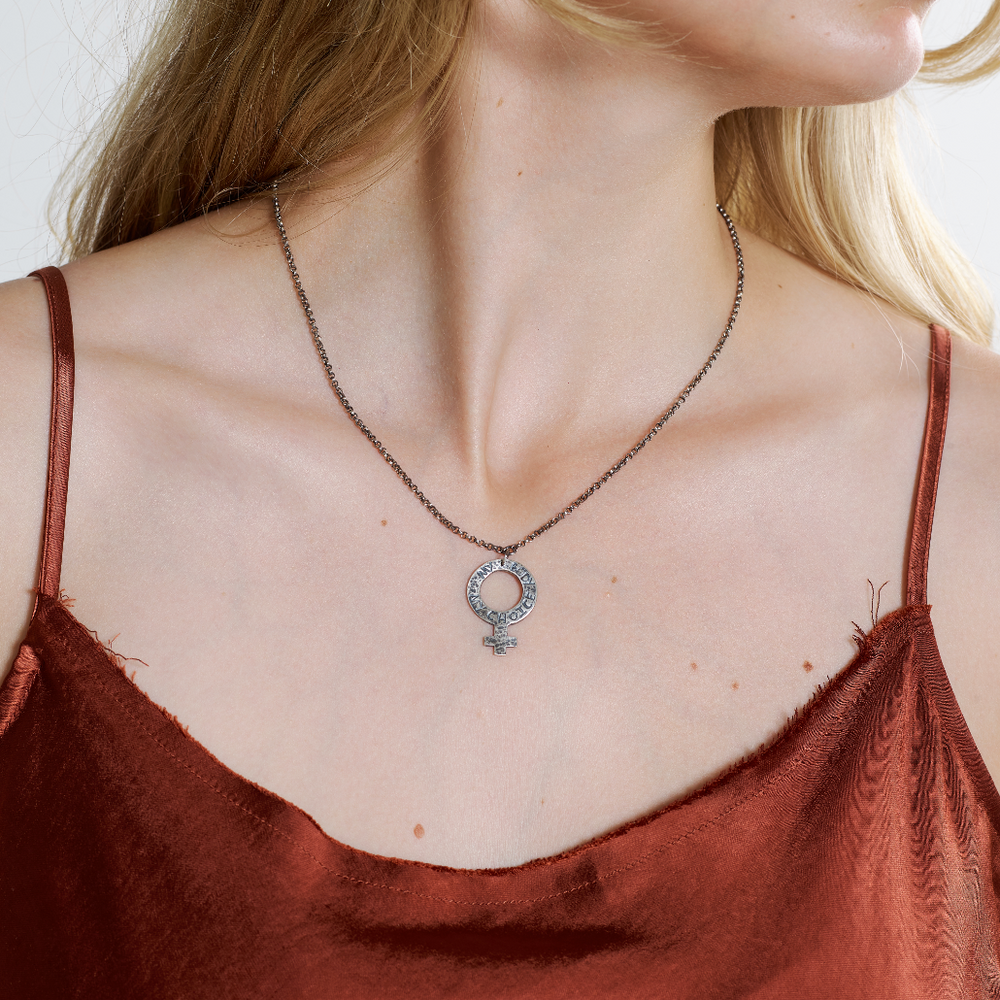 A woman wearing a sterling silver pendant necklace with an oxidized chain and a female symbol pendant.