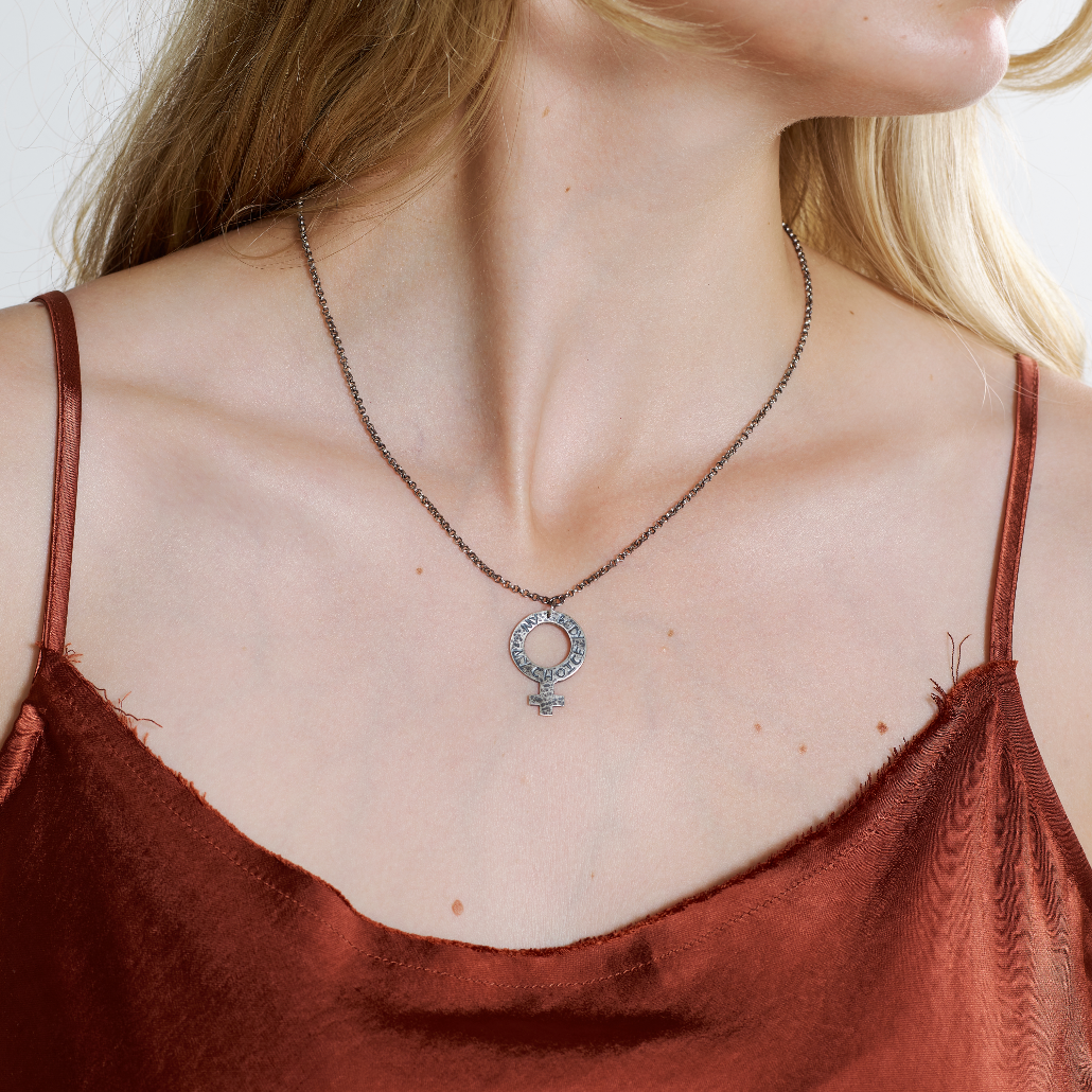 A woman wearing a sterling silver pendant necklace with an oxidized chain and a female symbol pendant.
